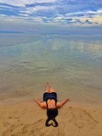 High angle view of woman with heart shape hair lying on shore at beach