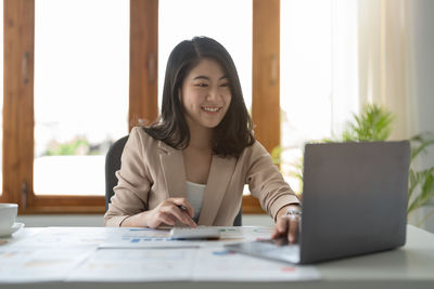 Portrait of woman using laptop at office