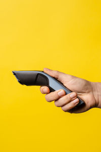 Midsection of woman holding hands against yellow background