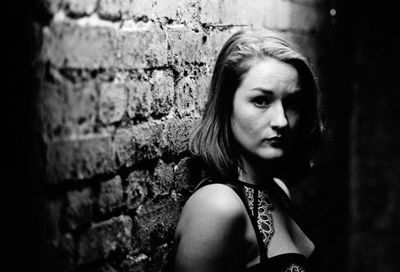 Close-up portrait of young woman leaning on brick wall