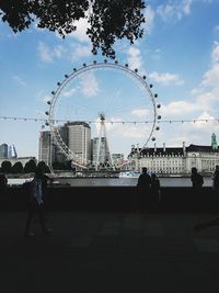 People in amusement park against cloudy sky