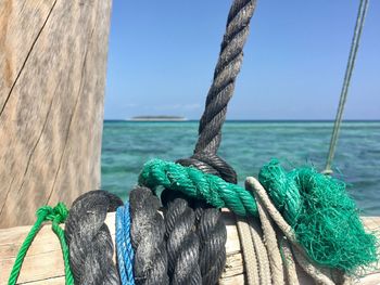Close-up of rope tied to bollard against blue sky