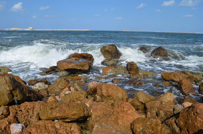 Rocks on sea shore against sky