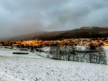 Scenic view of buildings by mountains against sky during winter