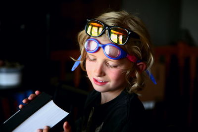 Close-up of boy holding book with glasses on forehead