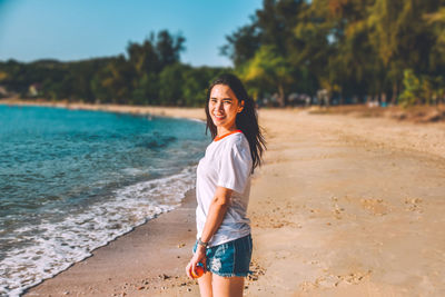 Portrait of smiling young woman standing on beach