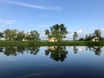 Scenic view of lake by trees and building against sky