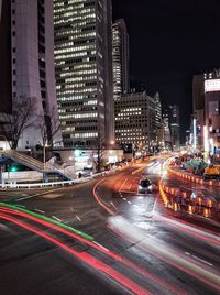 Light trails on city street by buildings at night