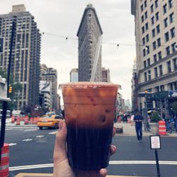 Close-up of hand holding drink against city street