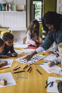 Female teacher guiding students to recognize colors while training them in kindergarten