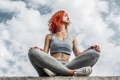 Female racer seated on a panel isolated on sky background