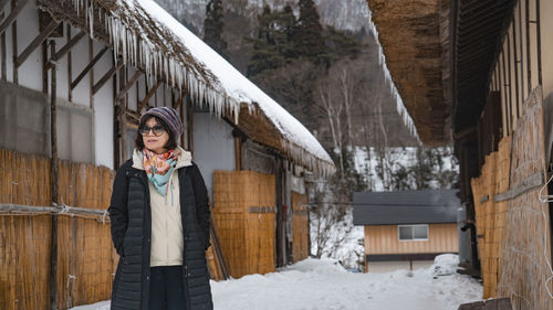 Portrait of smiling young woman standing against building