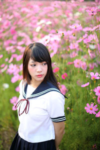 Side view of young woman standing amidst flowering plants