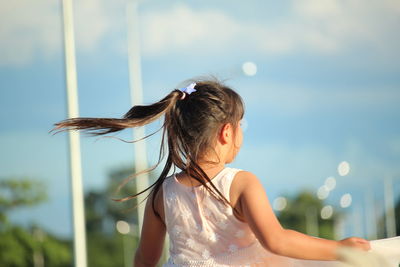 Rear view of girl standing against sky