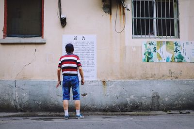 Full length rear view of boy walking in city