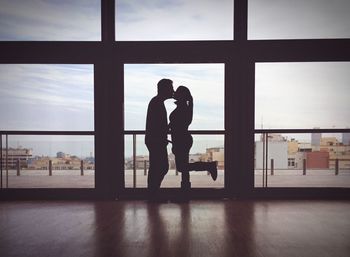 Silhouette of couple kissing while standing against door