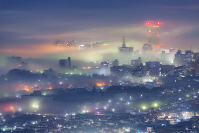 Illuminated cityscape against sky at night