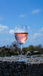 Close-up of wineglass on rock against sky