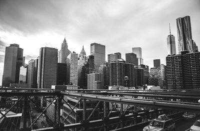 Brooklyn bridge by city skyline against sky