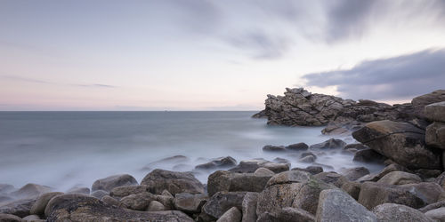 Rocks on beach against sky during sunset