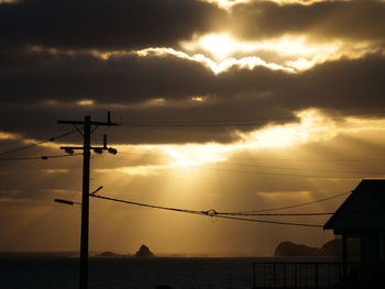 Low angle view of silhouette power lines against sky during sunset