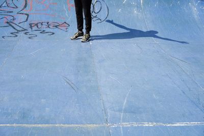 Low section of woman standing on footpath during sunny day