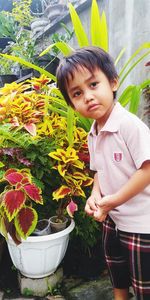 Portrait of cute girl standing by flowering plants
