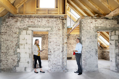 Businesswoman holding digital tablet while discussing with building contractor at construction site