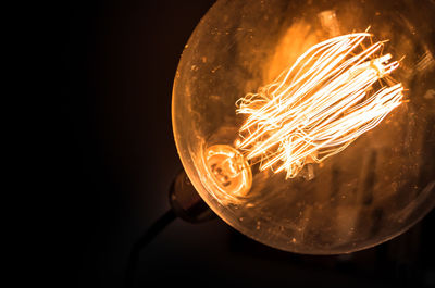 Close-up of illuminated light bulb against black background