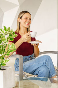 Young woman using mobile phone while sitting on sofa at home