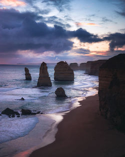 Rocks on beach against sky during sunset