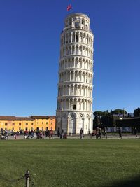 People in front of historical building against blue sky