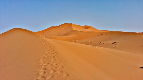 Scenic view of desert against clear blue sky