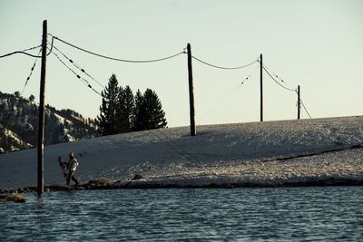 Man relaxing on riverbank against clear sky