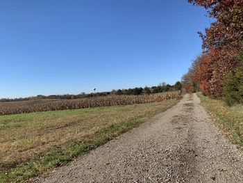 Road amidst field against clear sky