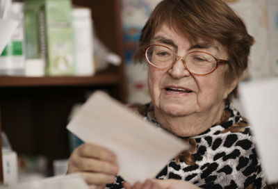 Close-up of senior woman reading paper while sitting at home