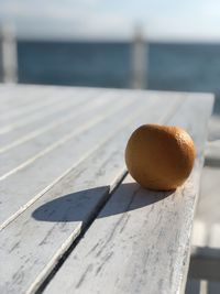 Close-up of apple on wooden railing against sea