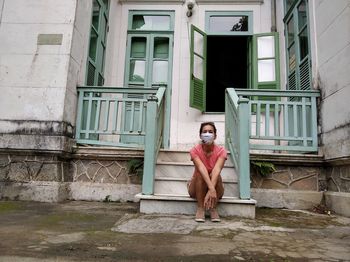 Portrait of smiling woman sitting outside house