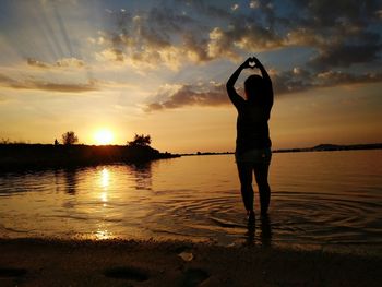 Rear view of silhouette man standing at beach during sunset