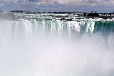 Scenic view of waterfall against sky