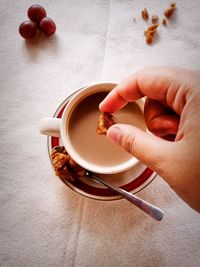 Cropped hand holding coffee cup on table