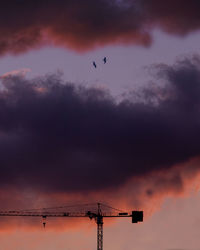 Low angle view of silhouette crane against sky during sunset