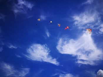 Low angle view of kites in blue sky