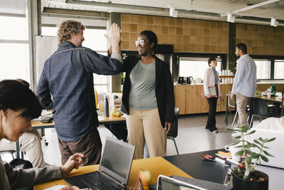 Happy businesswoman giving high-five to colleague at office