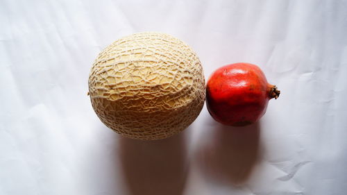 Directly above view of muskmelon and pomegranate on paper