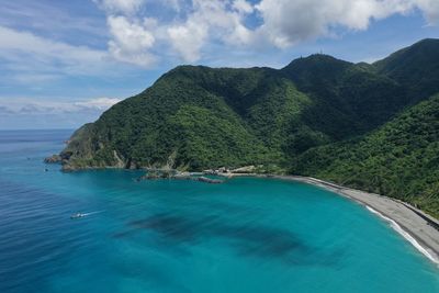 Scenic view of sea by mountains against sky