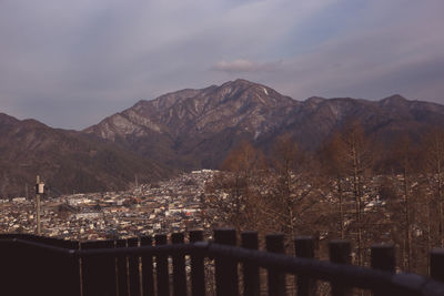 Aerial view of townscape by mountains against sky