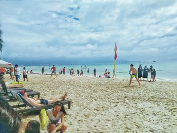 People on beach against cloudy sky