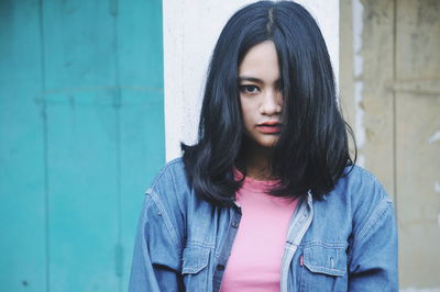 Portrait of beautiful young woman standing against wall