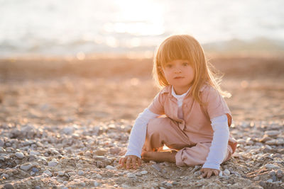 Pretty little child 2-3 year old playing at beach over sea at background in sun light outdoors. 